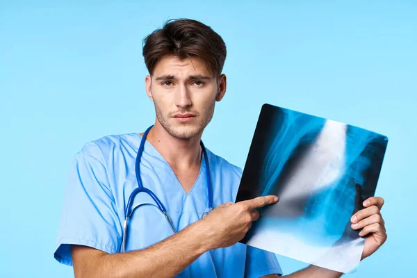 Tıbbi üniformalı bir adam. Sağlık tedavisi. Röntgen incelemesi mavi arka plan. — Stok fotoğraf