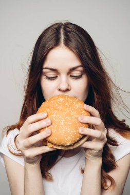 Elinde hamburger olan bir kadın. Atıştırmalık bir fast food.