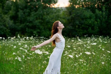 Beyaz elbiseli bir kadın doğada bir tarlada çiçek açıyor özgürlük yazı
