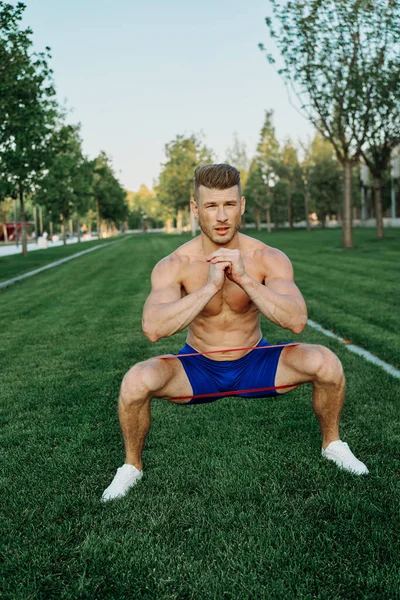 Atletik adam parkta koşma egzersizi yapıyor.