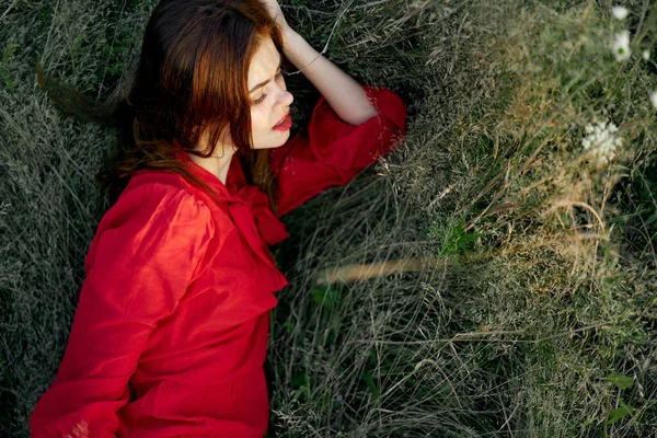 Jolie femme en robe rouge se trouve sur l'herbe posant vue de dessus — Photo