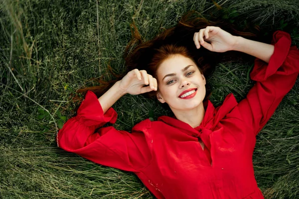 Donna allegra in un abito rosso si trova sull'erba vista dall'alto — Foto Stock