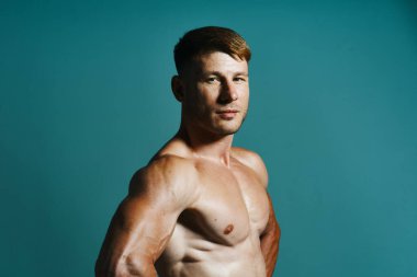 Vücudu kaslı, yeşil arka planı olan atletik bir adam.