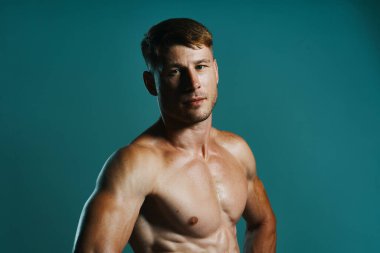 Vücudu kaslı, yeşil arka planı olan atletik bir adam.