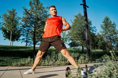 Sporcu adam parkta haltersiz egzersiz yapıyor.