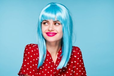 Mor peruklu neşeli kadın mavi arka plan pozu veriyor.
