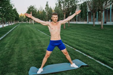 Mavi şortlu atletik adam parkta çalışıyor.