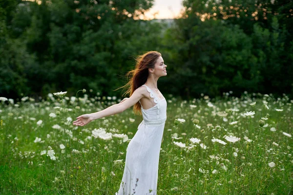 Beyaz elbiseli bir kadın doğada bir tarlada çiçek açıyor özgürlük yazı — Stok fotoğraf