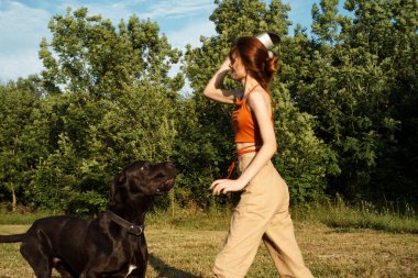 Dışarıda büyük siyah bir köpekle oynayan bir kadın. Eğlenceli bir arkadaşlık.
