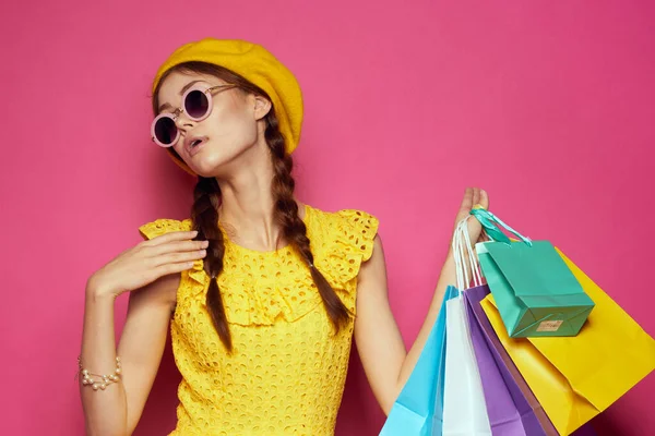 Wesoła kobieta nosi okulary przeciwsłoneczne stwarzające moda na zakupy różowe tło — Zdjęcie stockowe