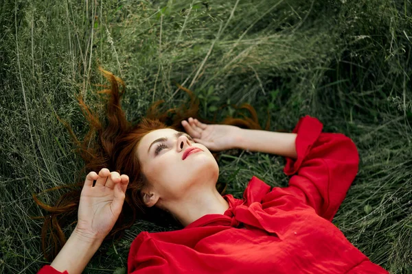 Nő piros ruhában fekszik a fű varázsa szabadság — Stock Fotó