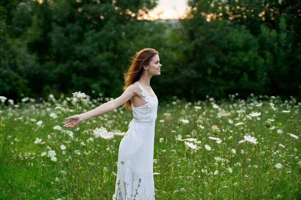 Kvinna i en vit klänning i ett fält på naturen blommor frihet sommar — Stockfoto