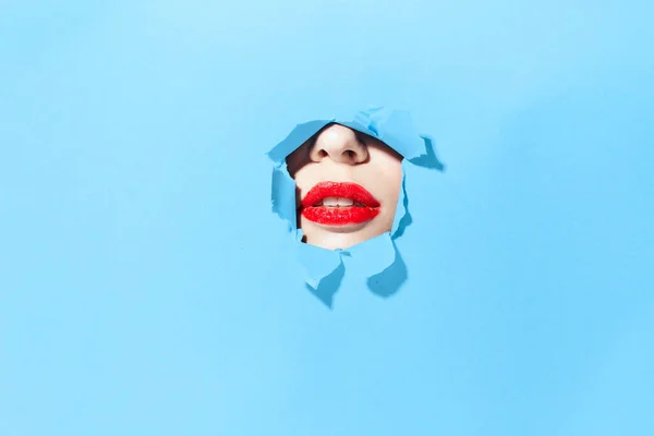 Mulher espreitando através dos buracos no cartaz azul estúdio fundo — Fotografia de Stock