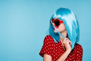 Göz kamaştırıcı mor saçlı kadın güneş gözlüğü takıyor mavi arka plan