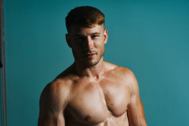 Vücudu kaslı, yeşil arka planı olan atletik bir adam.