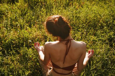 Çimlerde oturan kadın meditasyonda dinleniyor.