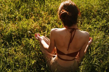 Çimlerde oturan kadın meditasyonda dinleniyor.