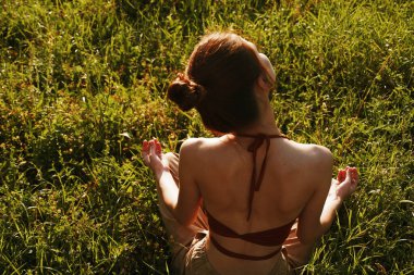 Çimlerde oturan kadın meditasyonda dinleniyor.