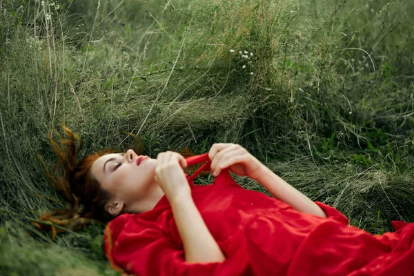 Jolie femme en robe rouge se trouve sur l'herbe dans le champ nature air frais — Photo