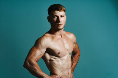 Vücudu kaslı, yeşil arka planı olan atletik bir adam.