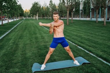 Mavi şortlu atletik adam parkta çalışıyor.