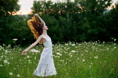 Beyaz elbiseli kadın dans doğası yaz pozu veriyor.