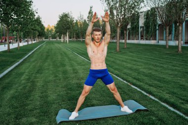 Mavi şortlu atletik adam parkta çalışıyor.