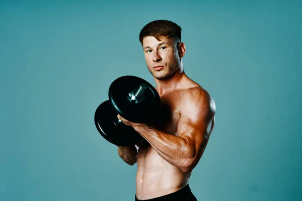 Kulturysta z muskularnym ciałem z hantlami w rękach fitness — Zdjęcie stockowe