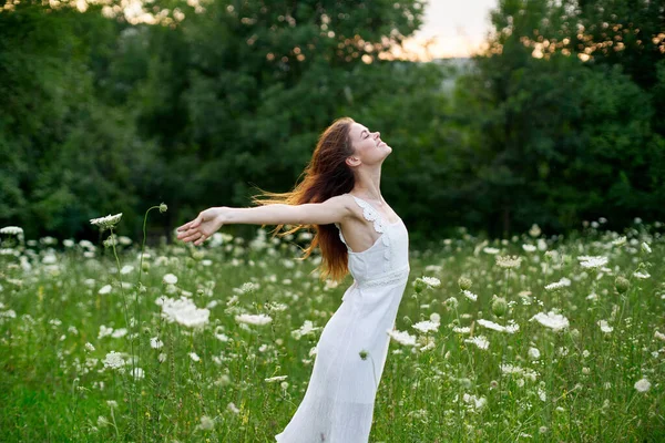 Donna allegra in un campo con fiori in un vestito bianco in natura — Foto Stock