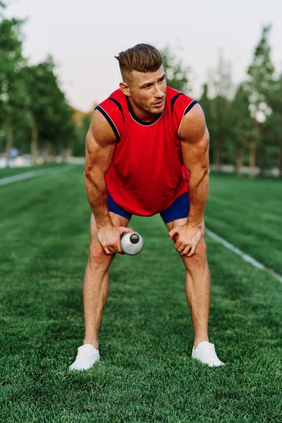 Hombre deportivo alegre en el parque en la hierba verde haciendo ejercicios —  Fotos de Stock