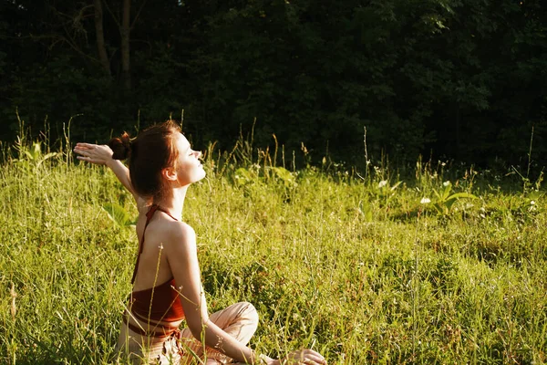 Kvinna på fältet sitter på gräset meditation vila — Stockfoto