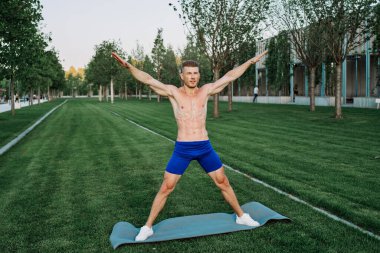 Mavi şortlu atletik adam parkta çalışıyor.