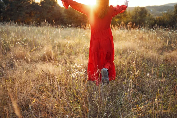 Žena v červených šatech v terénu chůze svoboda krajina — Stock fotografie