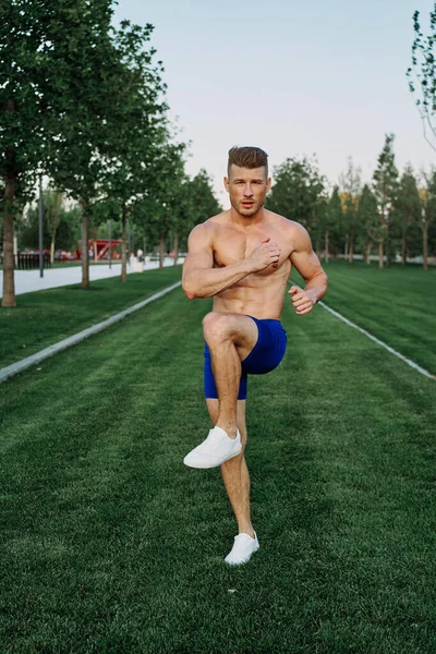 Parkta vücut egzersizi yapan atletik bir adam.