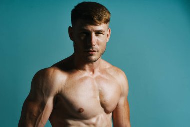 Vücudu kaslı, yeşil arka planı olan atletik bir adam.