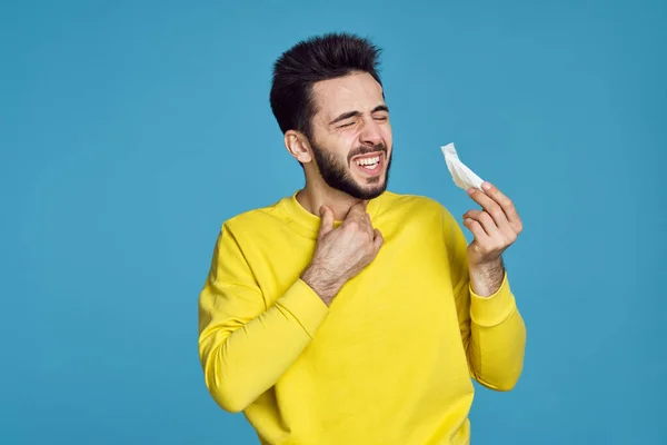 Чоловік в жовтому светрі проблеми зі здоров'ям емоції синій фон — стокове фото