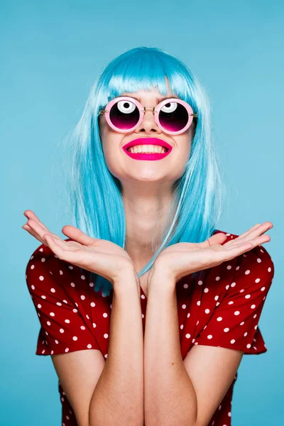Эмоциональная гламурная женщина в синих очках в париках позирует — стоковое фото