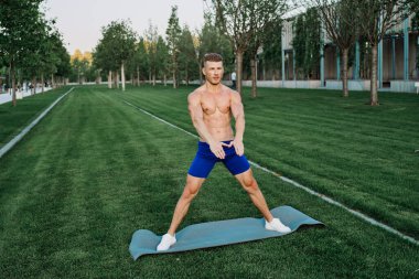 Mavi şortlu atletik adam parkta çalışıyor.