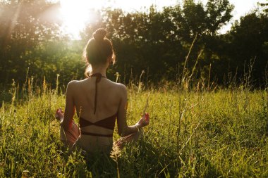 Yazın çimenlerin üzerinde oturan kadın meditasyon özgürlüğü.