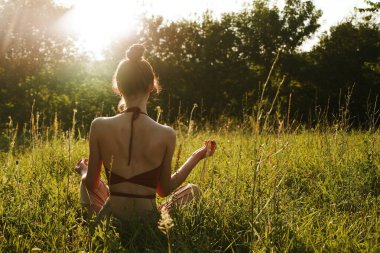 Yazın çimenlerin üzerinde oturan kadın meditasyon özgürlüğü.