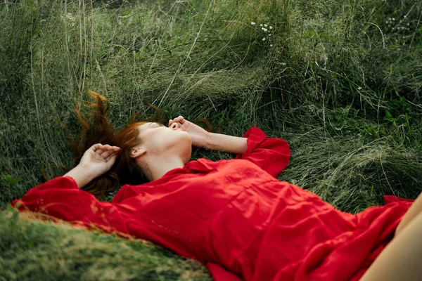 Mujer en vestido rojo se encuentra en la libertad encanto hierba — Foto de Stock