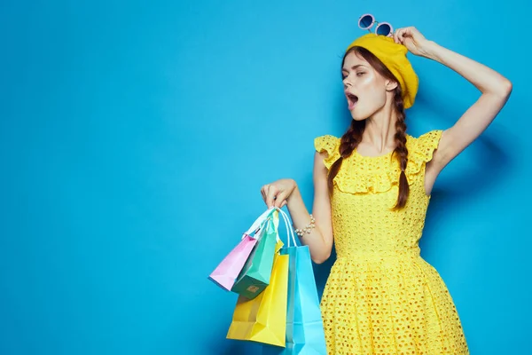 Usmívající se žena žluté šaty nakupování zábava modré pozadí — Stock fotografie