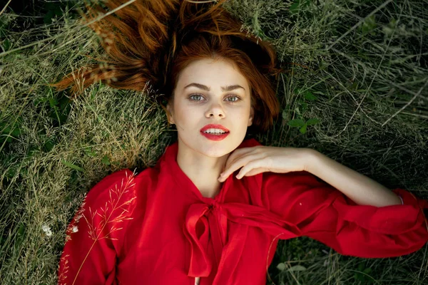 Pretty woman in red dress lies on the grass landscape freedom — Stock Photo, Image