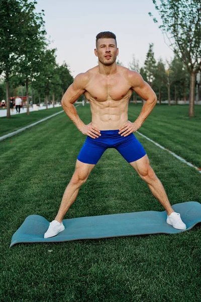 Спортсмен в синих шортах тренируется в парке — стоковое фото