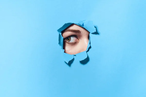Mujer espiando a través de los agujeros en el fondo del estudio azul cartel — Foto de Stock