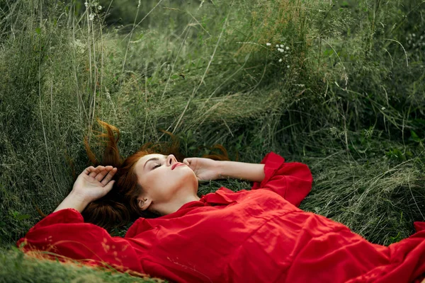 Femme en robe rouge repose sur l'herbe charme liberté — Photo