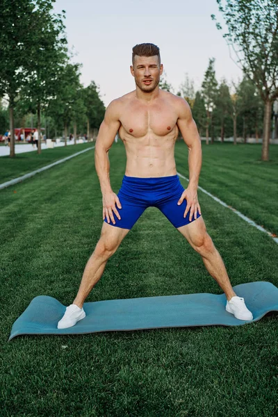 Hombre deportivo en pantalones cortos en el parque haciendo ejercicio al aire libre — Foto de Stock