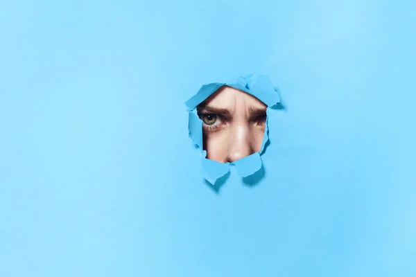 Poster mavisi stüdyo arka planındaki deliklerden bakan bir kadın. — Stok fotoğraf