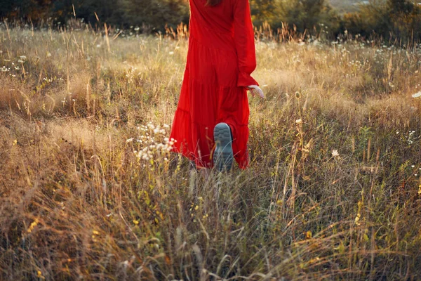 Žena v červených šatech v terénu chůze svoboda krajina — Stock fotografie