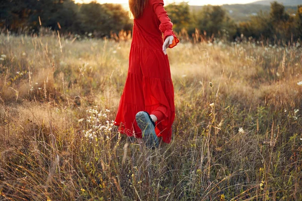 Woman in red dress in the field walk freedom landscape — Stock Photo, Image